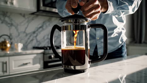 man brewing coffee with a french press in a modern kitchen