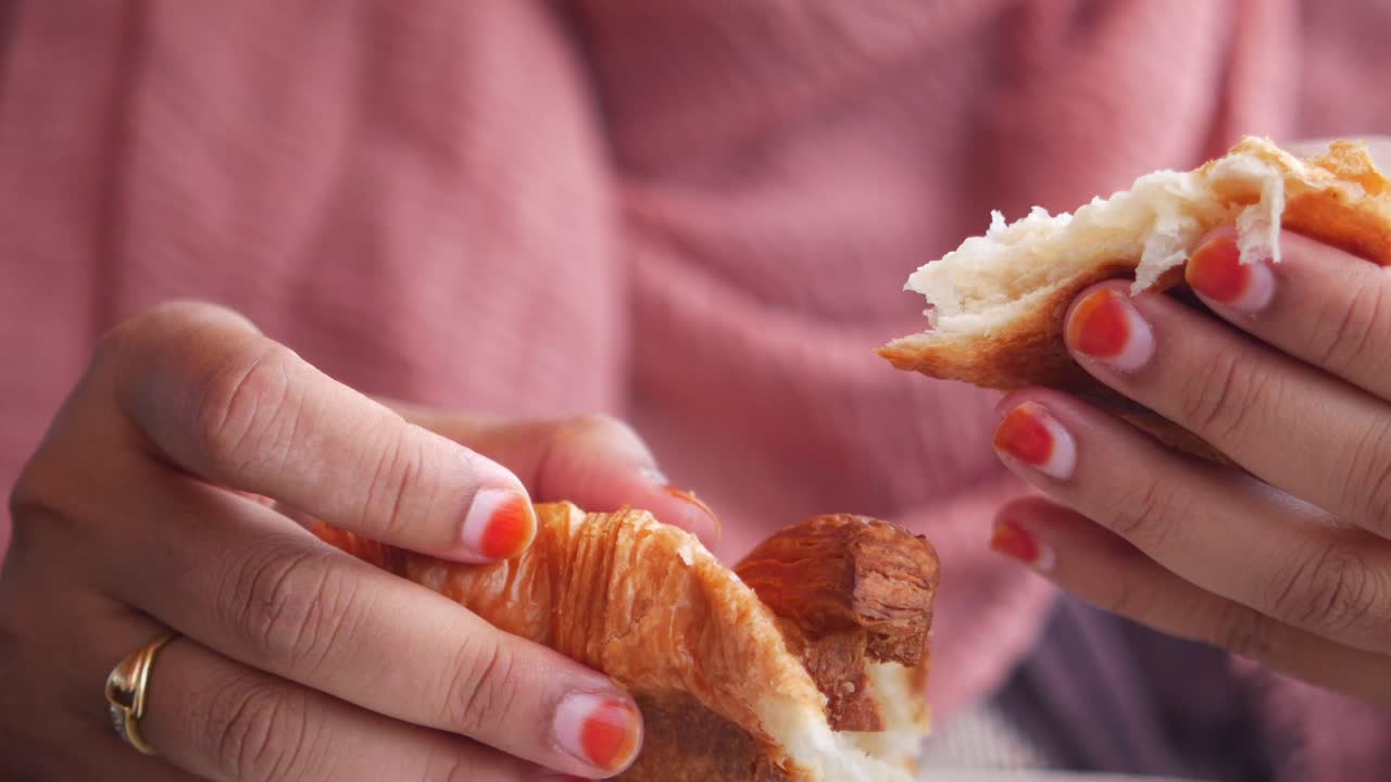 una mujer comiendo un croissant.