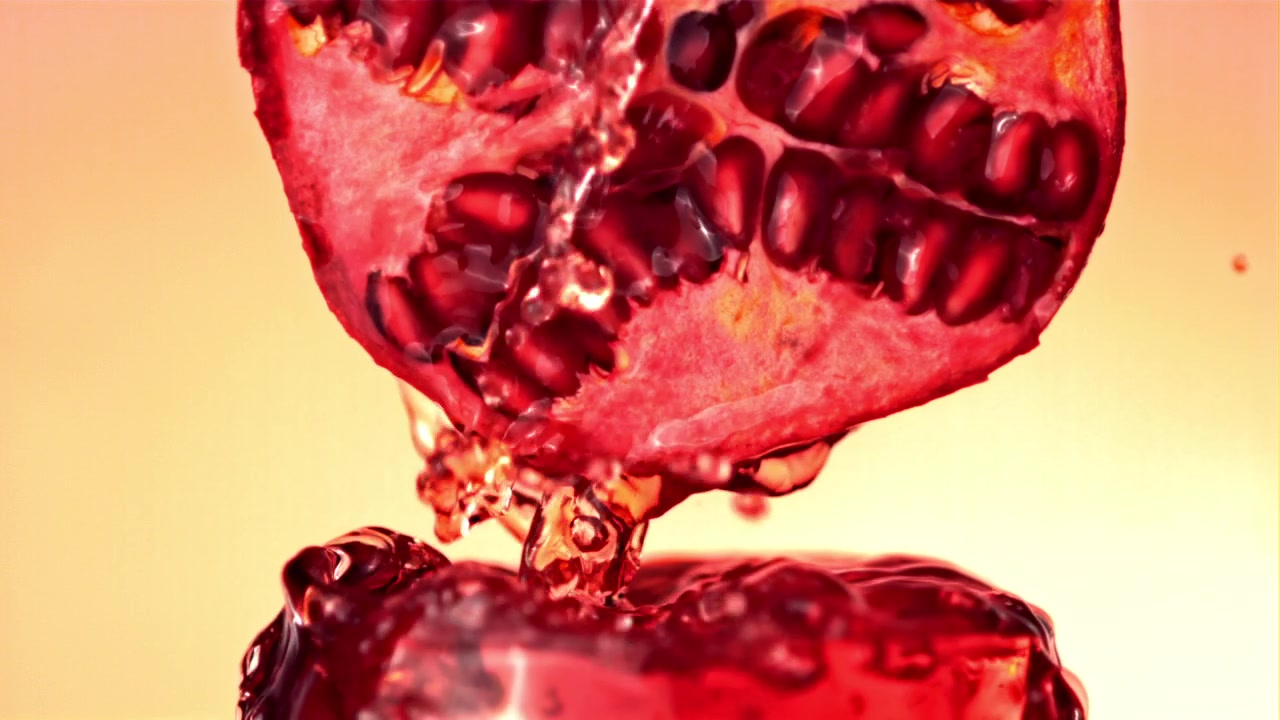 Slowmotion granatæblejuice drypper ned i et glas