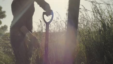 farmer digging in hay field with fork in sunshine