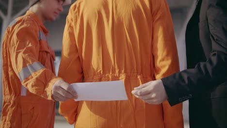 man in a suit giving to the construction worker in uniform and envelope with money bribe. happy worker hiding money. corruption