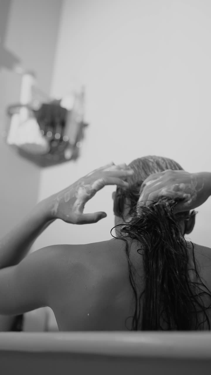 Donna che si lava i capelli sotto la doccia in bianco e nero