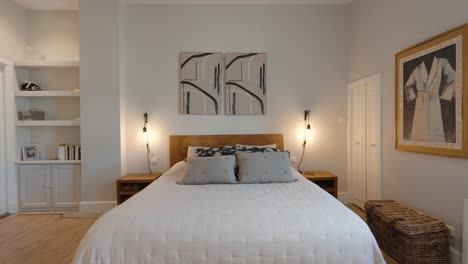 sow establishing shot of a master bedroom with artwork hanging above the bed