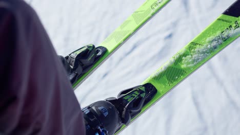 close-up of boots and skis of a person going up the chairlift to ski on a snowy slope in good weather