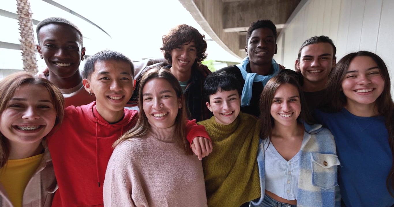 Gruppo di giovani amici diversi che sorridono insieme all'aperto
