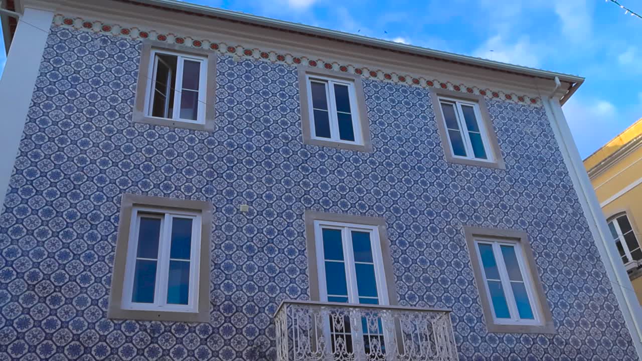 Slow motion view of a traditional Portuguese house facade covered with blue azulejos tiles in Lisbon. Exterior architectural detail filmed on a sunny day, showcasing cultural heritage and design