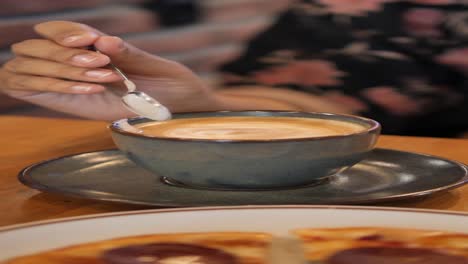 a woman stirs her cappuccino with a spoon in a cafe.