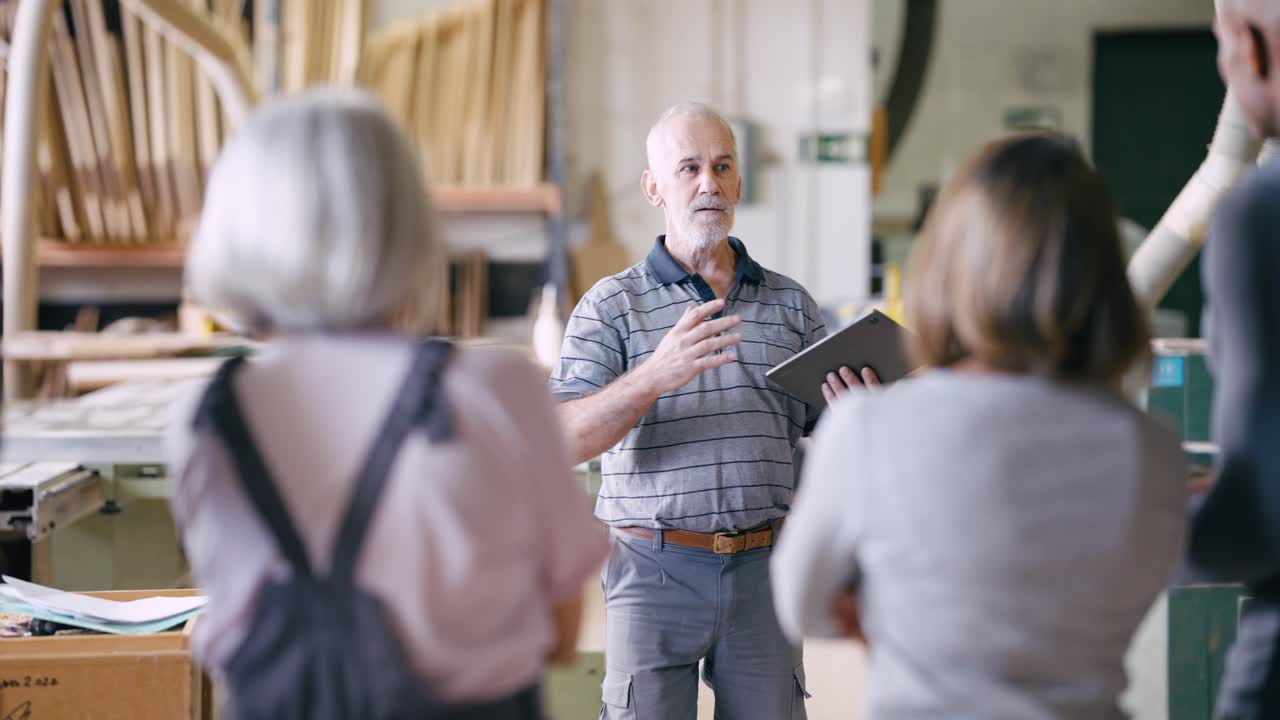 Uomo anziano che conduce una discussione con un gruppo in un laboratorio