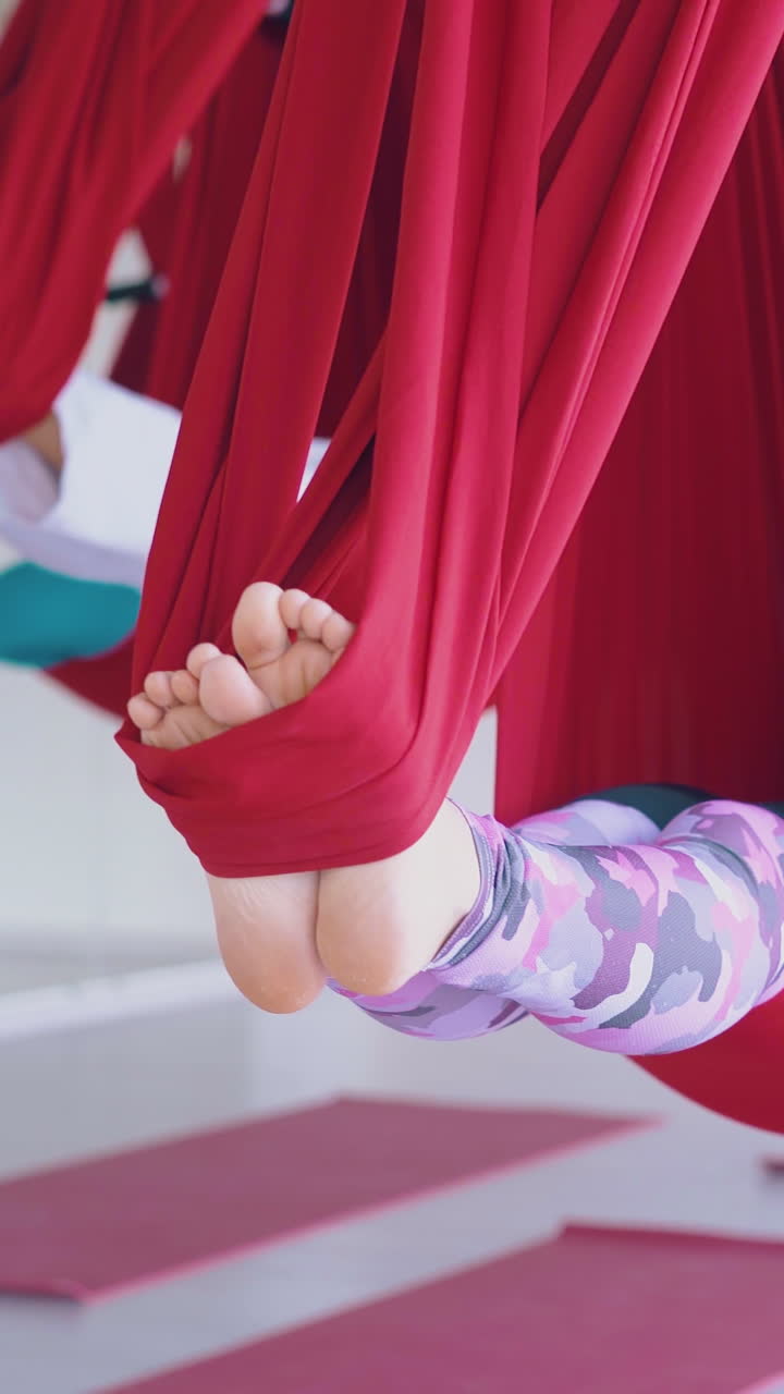 women feet swing in special yoga red hammocks relaxing after hard pilates workout in new training zone close view