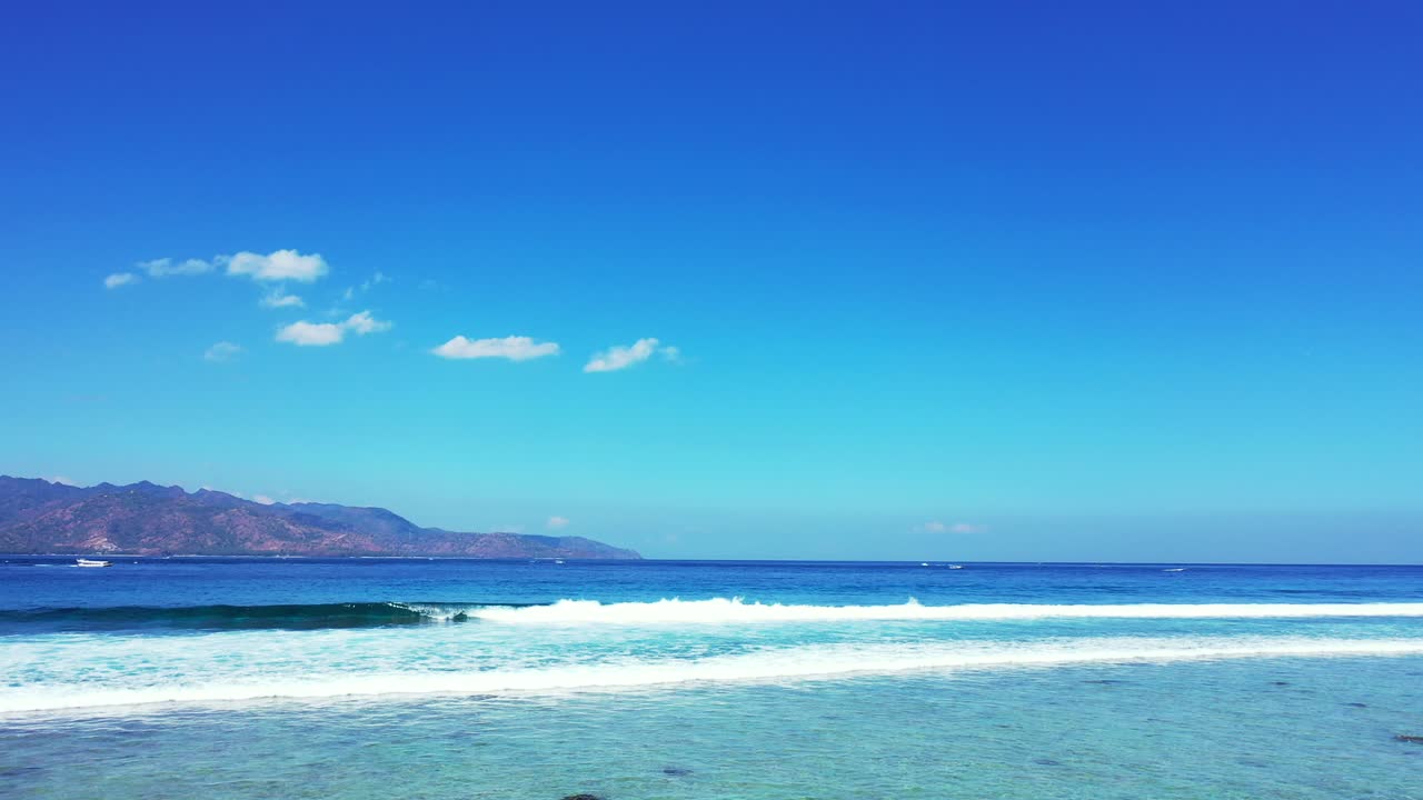 Paradise seascape with beautiful white waves coming from deep blue sea under bright sky on tropical islands, Indonesia