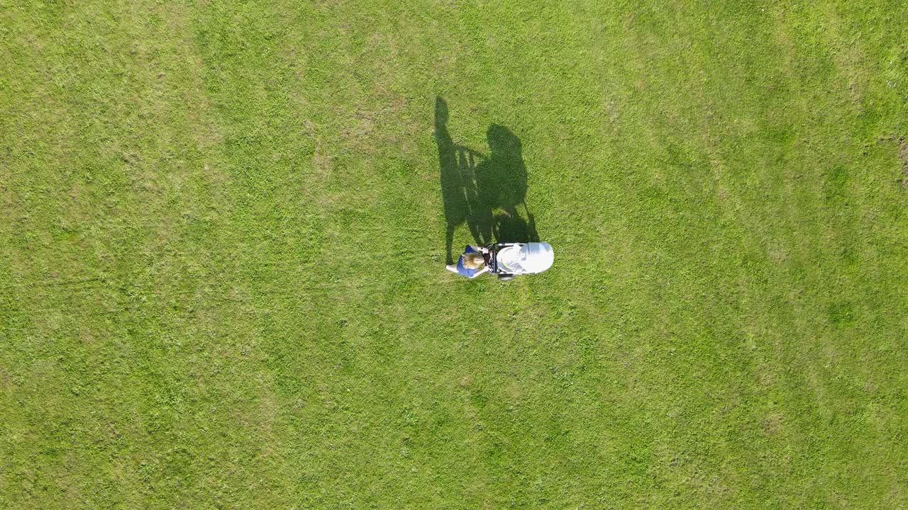 어린 엄마가 아기와 함께 산책차를 타고 공원에서  ⁇ 고 있다