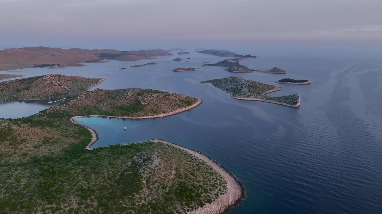 Aerial establishing overview of bays and beaches along Kornati islands with deep blue waters and rugged coastline under a clear sky