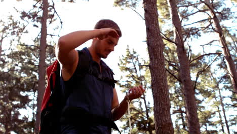 Man-hiking-through-a-forest-using-compass