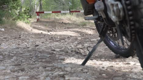 close up on motorcycle wheels, static on soil ground, road barrier in the background, pul focus from foreground to background 120fps