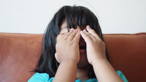 a young girl crying and covering her face with her hands