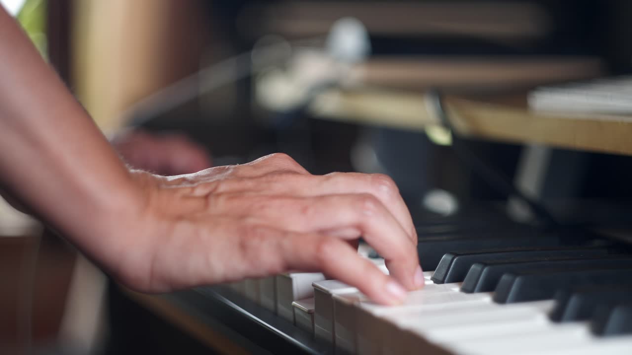 Close up view of two hands playing a piano keyboard and pressing gently the keys.