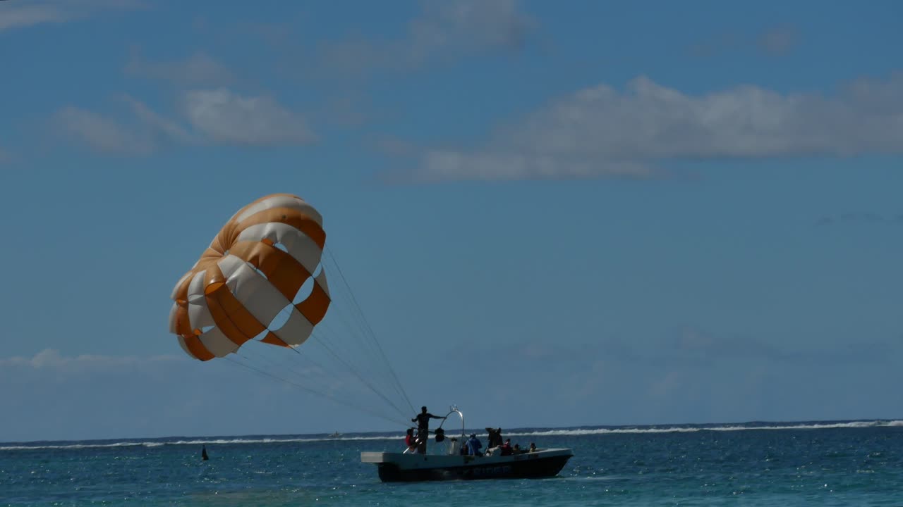 un plano siguiendo desde la orilla de un barco deportivo que va a empezar a hacer parasailing, hasta el momento del despegue