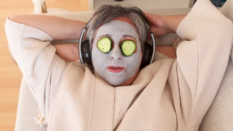 woman with facial mask and cucumbers on face listening to music