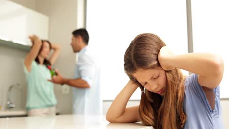 una niña cubriendo sus orejas mientras sus padres pelean