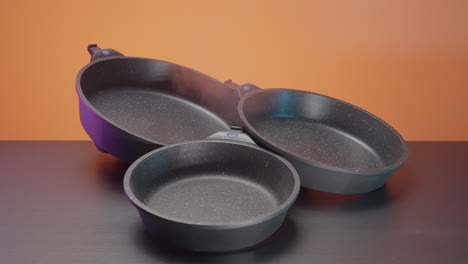 three black stone frying pans