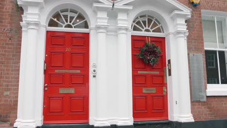 Corona-De-Navidad-En-La-Puerta-Roja-Del-Edificio-En-Manchester,-Inglaterra