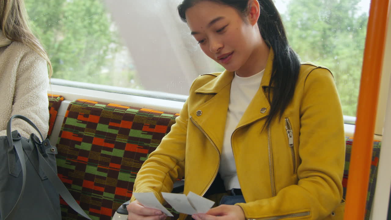 Smiling Woman Sitting In Carriage On Underground Train Looking At Photos