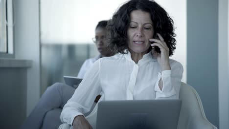 mujer de negocios seria con computadora portátil y teléfono inteligente