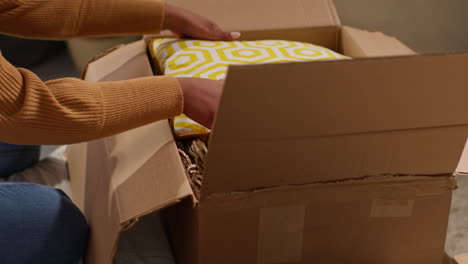 woman unpacking a cardboard box, moving or housewarming