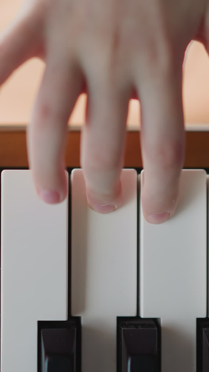 Child presses button on electronic piano and plays smooth melody. Female student engages in music lesson. Learning new musical composition close upper view