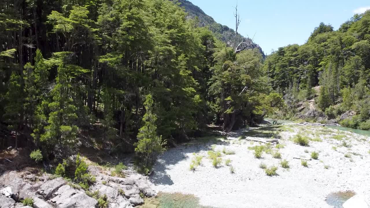 drone take off shot of this amazing blue river in the middle of the forest discovering the snow mountains behind the marvelous trees, shot with DJI mini 3 60fps in Cajon del Azul in Argentina