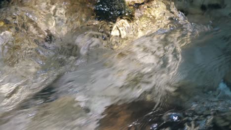 close-up of clear water flowing smoothly over rocks, showcasing the dynamic motion and reflective surface