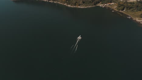 drone aerial top view of a boat driving through lake atitlan, guatemala