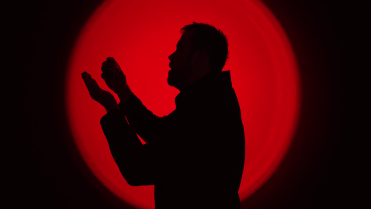 Silhouette drammatica di profilo di un uomo che prende e ingoia pillole, con una retroilluminazione circolare rossa intensa, a simboleggiare la dipendenza e la crisi da sostanze. Ideale per temi come la dipendenza, l'abuso di oppioidi