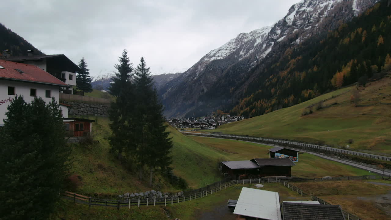 Aerial flight alone Austrian houses located between snowy mountains of Kauntertal Austria during cloudy day