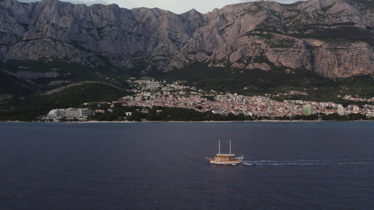 Boat Sailing In The Adriatic Sea Off The Coastline Of Makarska In Croatia, Aerial Shot.