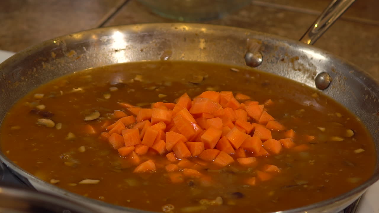 mujer agregando zanahorias cortadas en cubitos a la salsa marrón en una sartén y revolviendo, cerrada