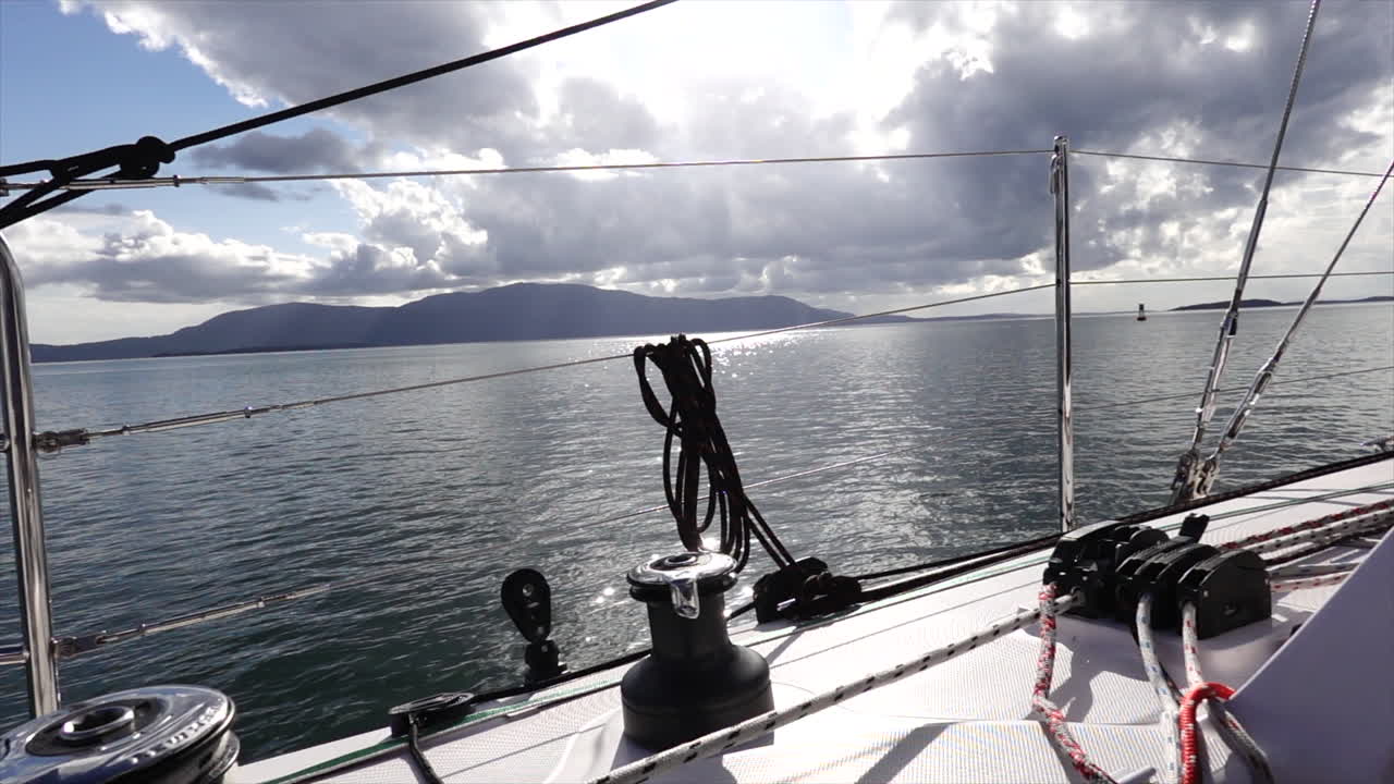 Blick von einem Segelboot, während Sonnenstrahlen an einem ruhigen Tag die Wolken über den San Juan Inseln durchbrechen