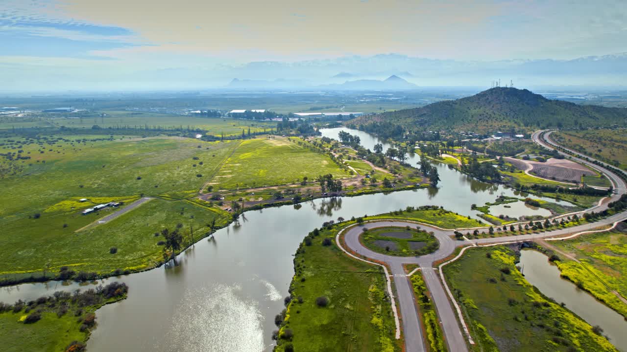 Caren Lagoon with surrounding green fields and water, mountains in the distance, aerial view