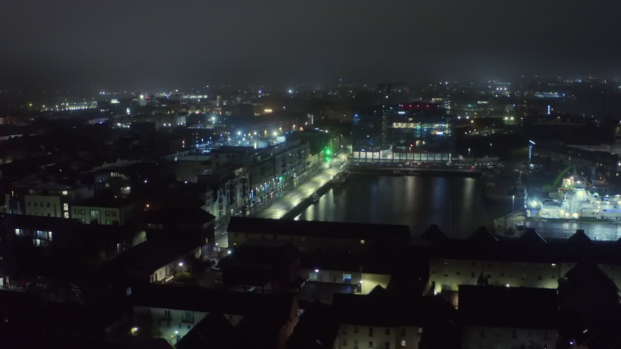 Ascending aerial shot unveiling Galway city harbour shrouded in nighttime fog