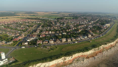 High-Aerial-Drone-Shot-Around-Coastal-Road-Above-Orange-and-White-Cliffs-of-Old-Hunstanton-with-Houses-and-Fields-and-Sheraton-Steam-Trawler-Shipwreck-North-Norfolk-UK