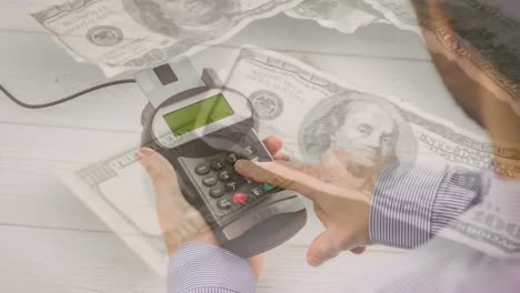 Animation-of-dollar-banknotes-falling-over-hand-of-caucasian-man-holding-payment-terminal