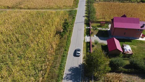 4k drone silver car chase through a village, single street with no cars