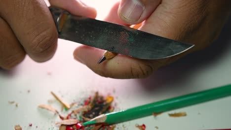 Footage-of-hands-slowly-sharpening-a-pencil-and-some-coloured-pencils-with-a-sharp-knife