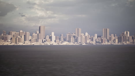 city skyline at dusk overlooking water with modern architecture and clouds