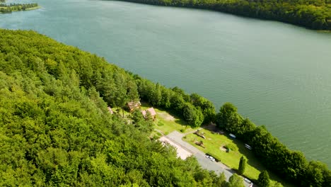 Toma-Aérea-Hacia-Atrás-De-Un-Hermoso-Lago-Natural-Y-Hermosos-árboles-Forestales-En-La-Costa---Lago-Raduńskie-Dolne,-Borucino