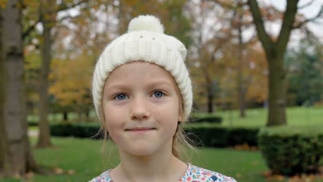 close-up of young girl with blue eyes wearing white beanie in fall