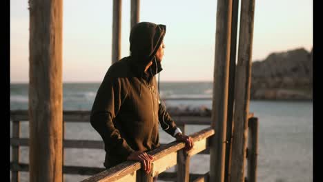 african american male jogger standing on pier at beach in the sunshine 4k