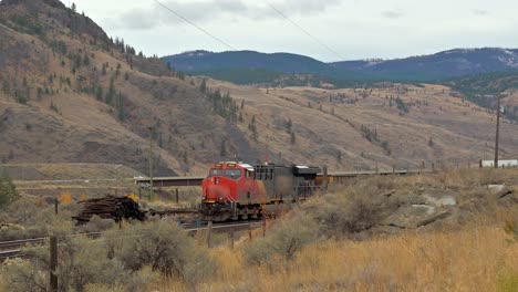 panorámica de un tren rojo esperando en el ferrocarril en un pintoresco entorno desértico cerca de sovana, kamloops, columbia británica, canadá