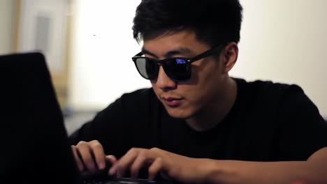 focused individual engaged in task on laptop while wearing sunglasses: a captivating moment of concentration and productivity