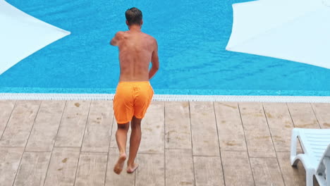man jumping in swimming pool at sunny day.